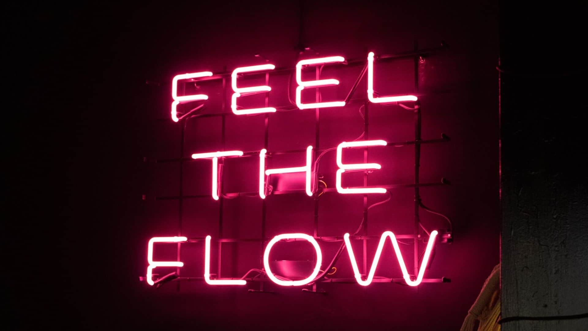 Zdjęcie przedstawiające neon "Feel The Flow" znajdujący się na ściance wspinaczkowej Flow Climbing Space Wrocław.